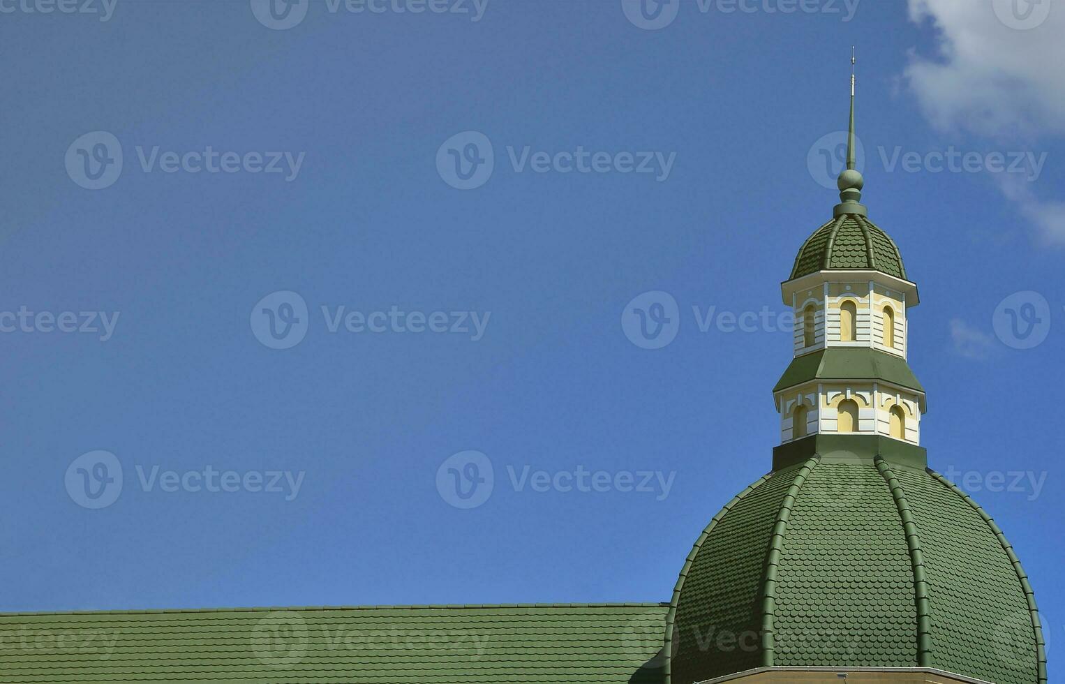 Completed perfect high-quality roofing work from metal roofing. The dome of a polyhedral shape with a spire is covered with green metal tiles photo