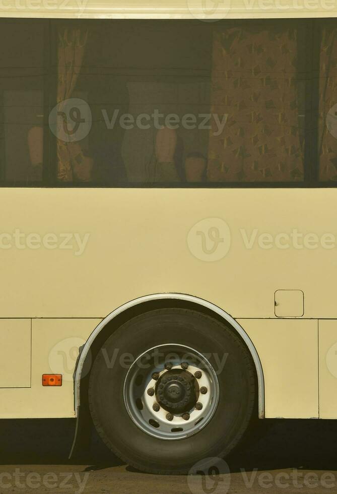 Photo of the hull of a large and long yellow bus with free space for advertising. Close-up side view of a passenger vehicle for transportation and tourism