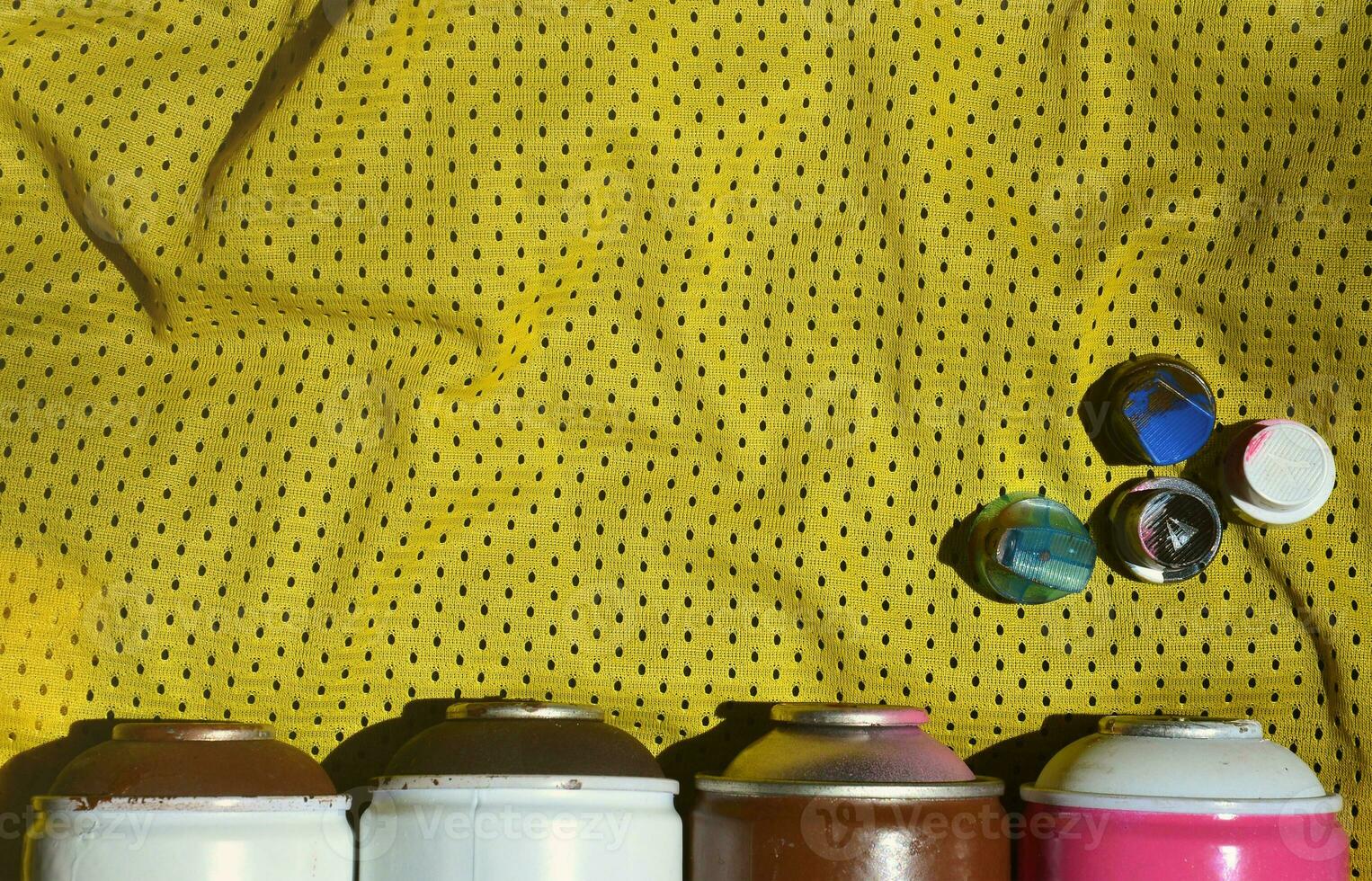 Several caps for used aerosol paint sprayers lie on the sports shirt of a basketball player made of polyester fabric. The concept of youth street art, active sports and eventful lifestyle photo