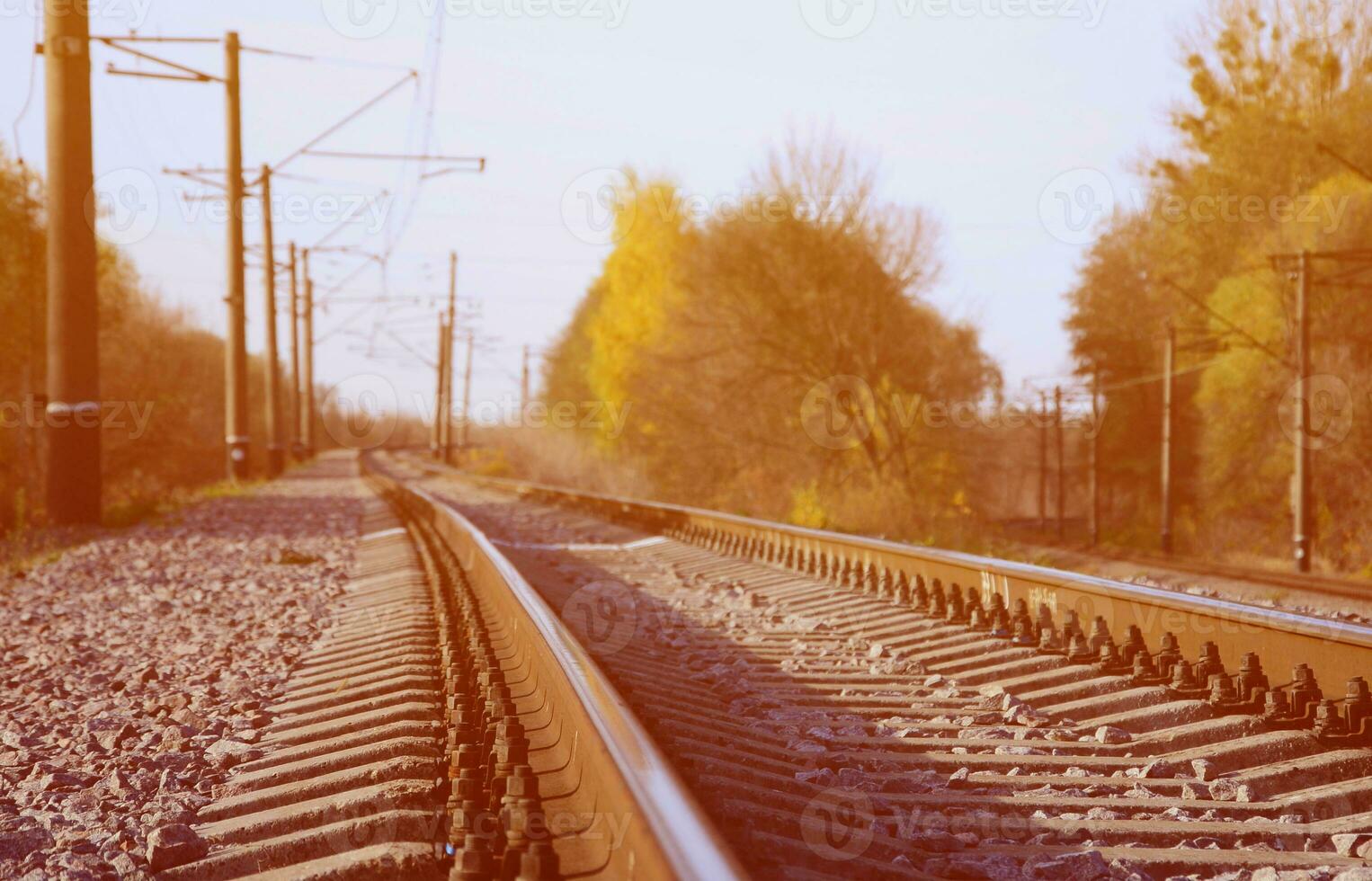Autumn industrial landscape. Railway receding into the distance among green and yellow autumn trees photo