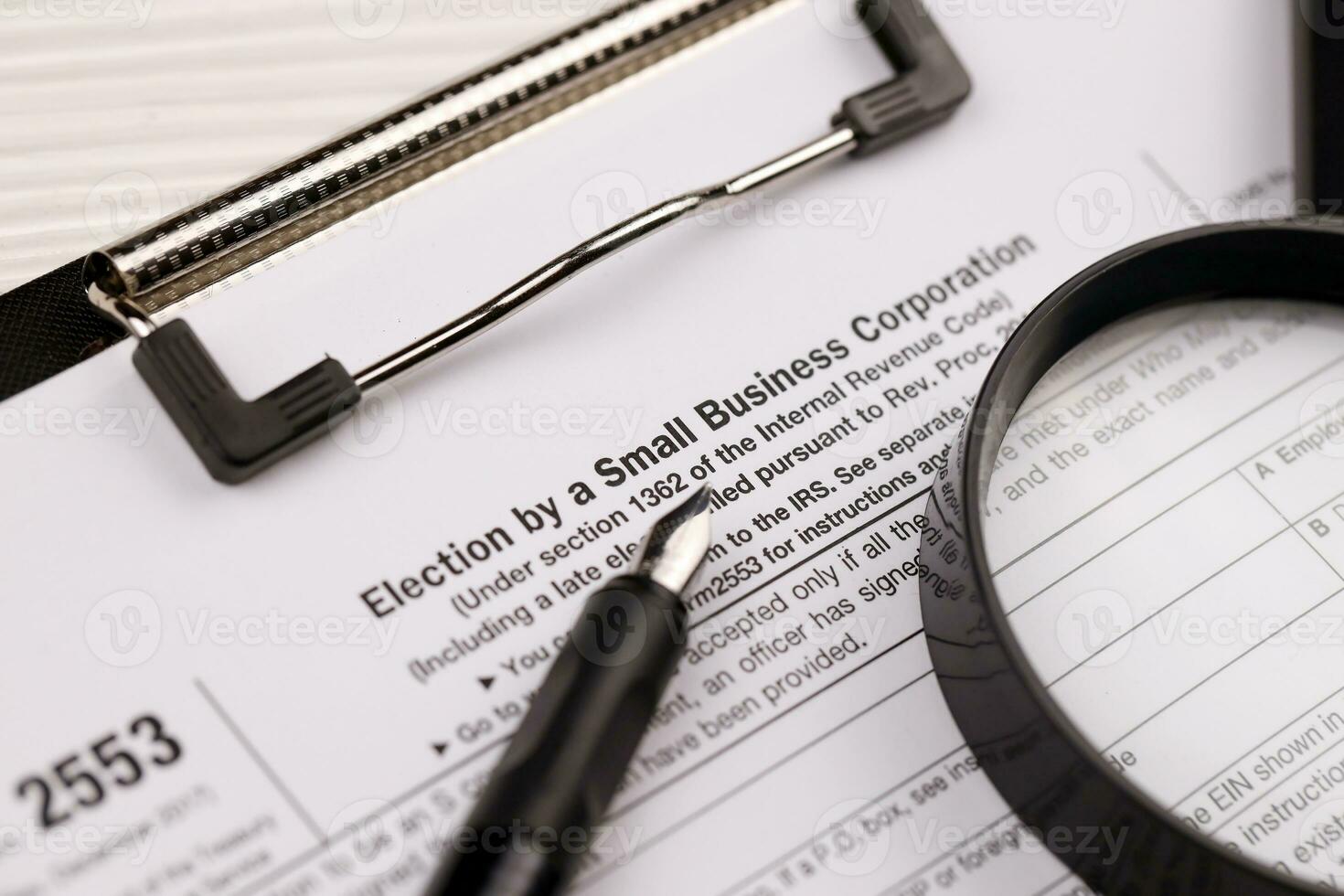 IRS Form 2553 Election by a Small Business Corporation tax blank on A4 tablet lies on office table with pen and magnifying glass photo