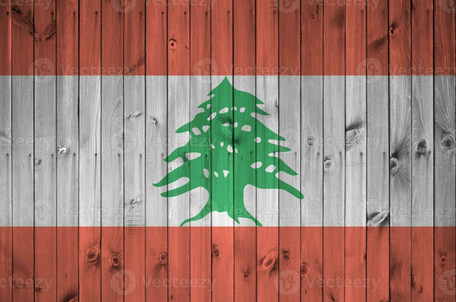 Lebanon flag depicted in bright paint colors on old wooden wall. Textured banner on rough background photo