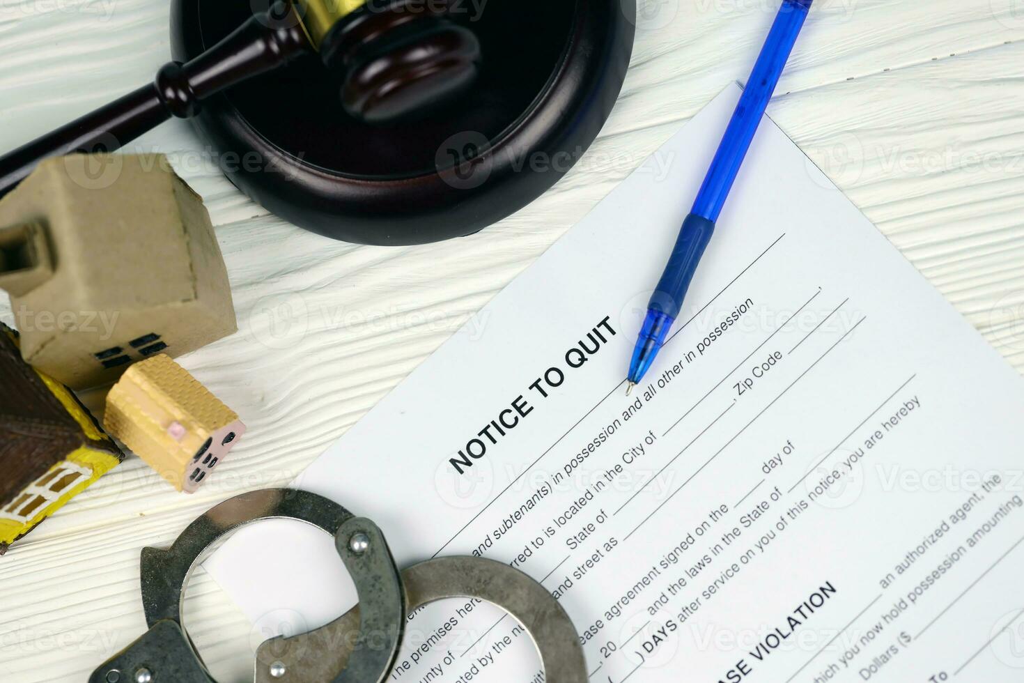 Notice to quit or eviction notice blank document paper ready to fill with judgement gavel, handcuffs and small toy houses on table photo