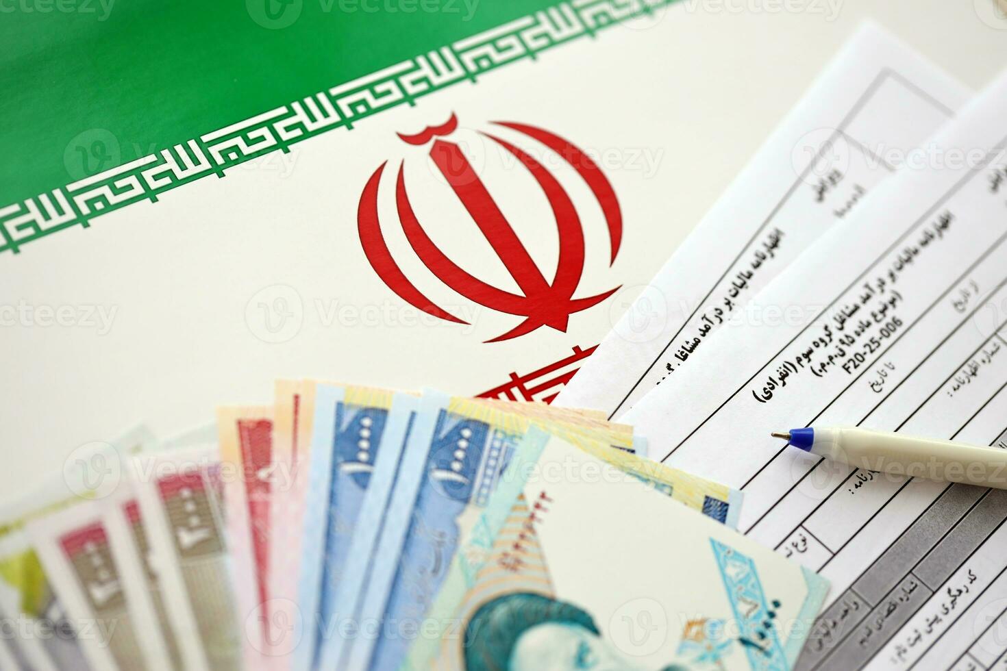 Iranian annual income tax return form F20-25-006 ready to fill on table with pen and iranian money on flag photo