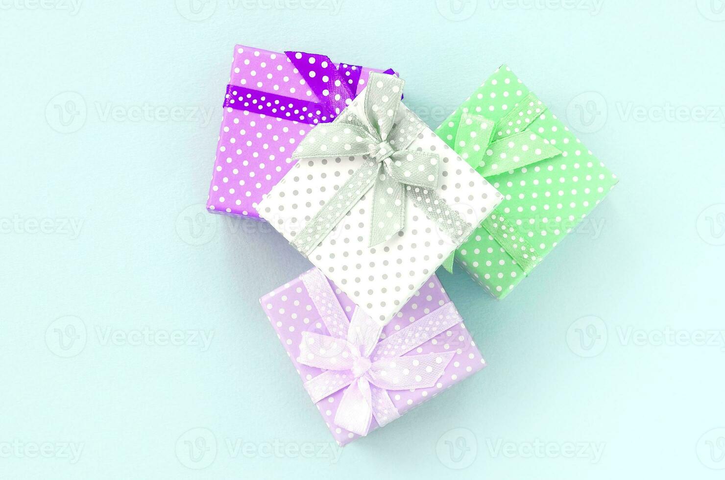 Pile of a small colored gift boxes with ribbons lies on a violet background. Minimalism flat lay top view photo