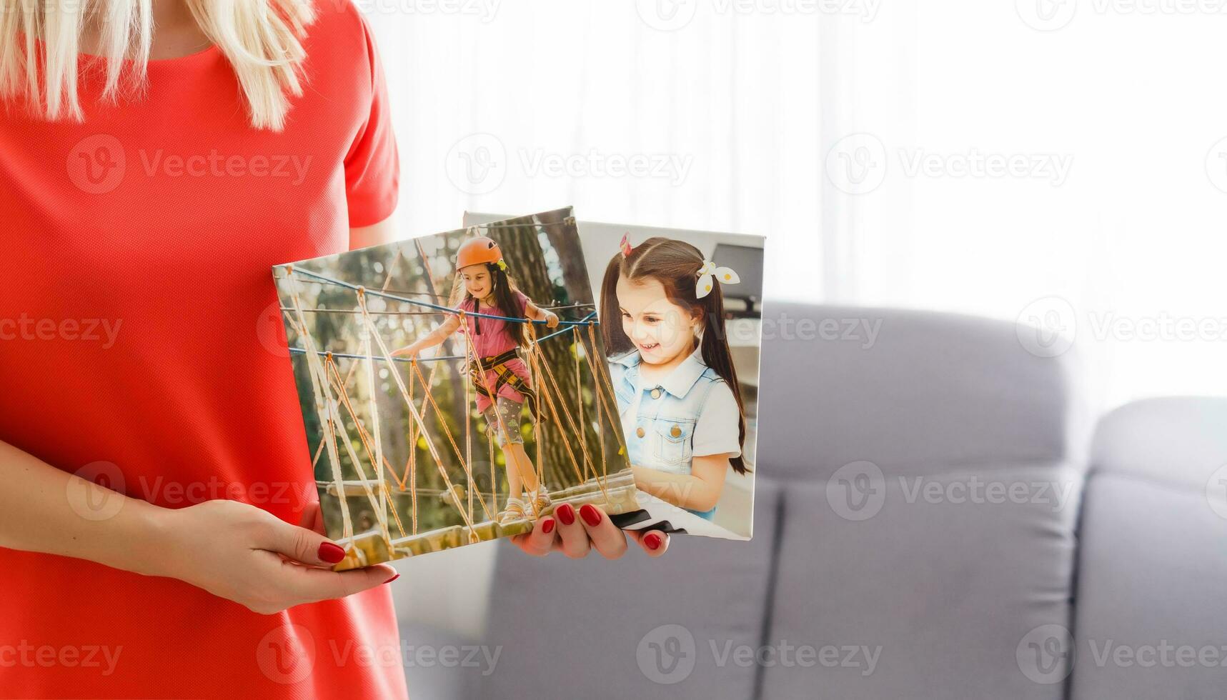 A happy young blonde woman is holding a large wall canvas at home photo