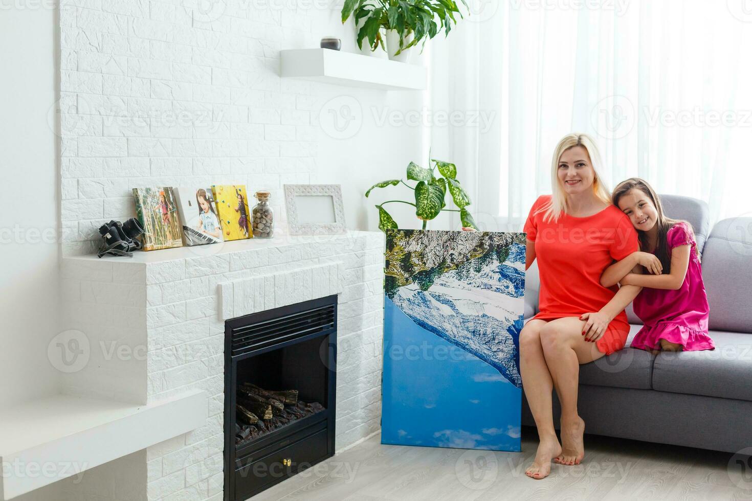mother and daughter hangs a large photo canvas at home