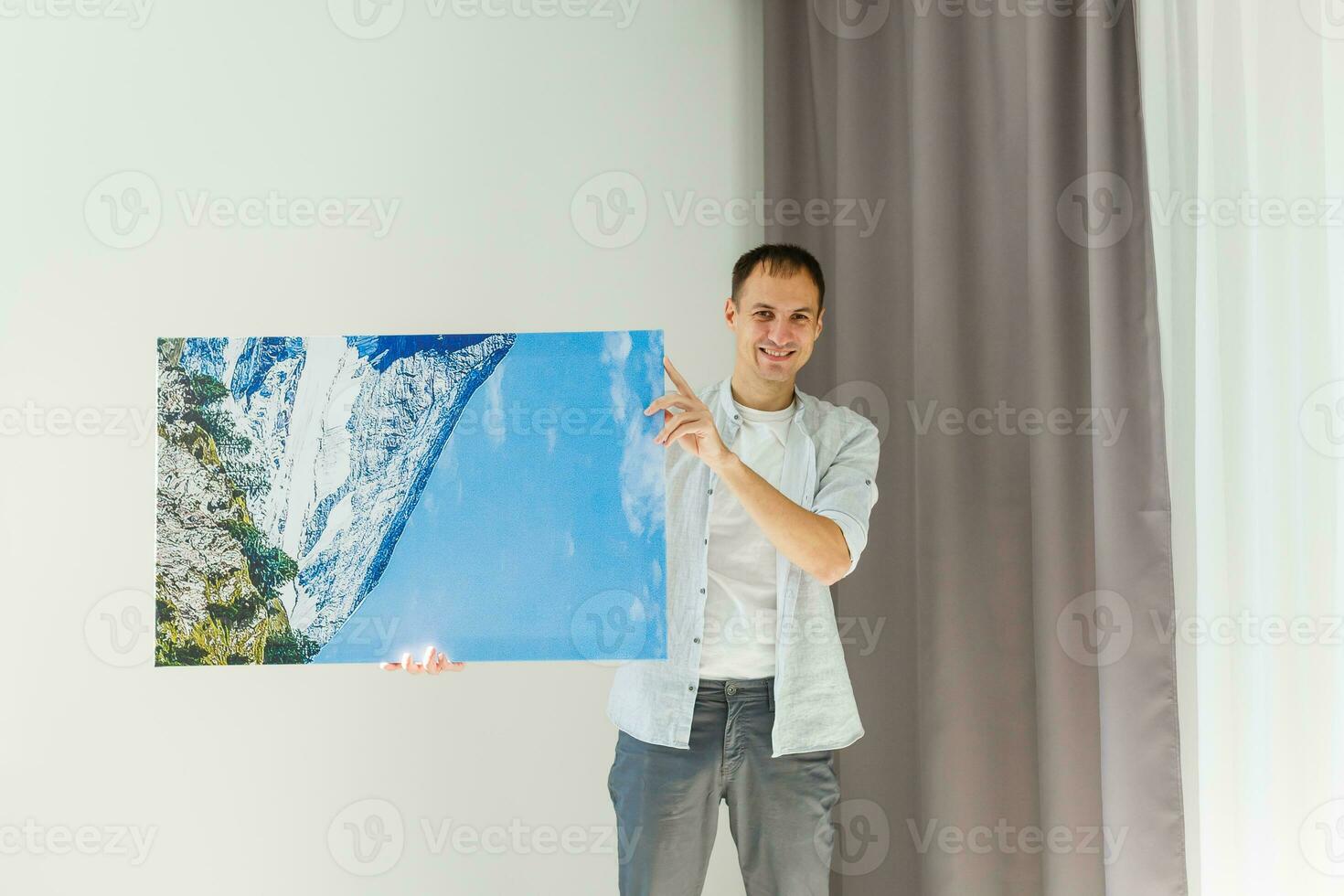 man holds photo canvas at home