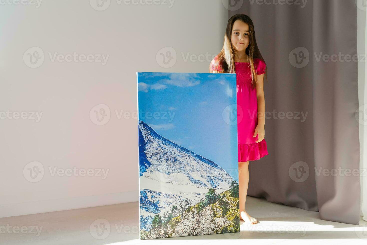 Cute little girl holding photo canvas at home