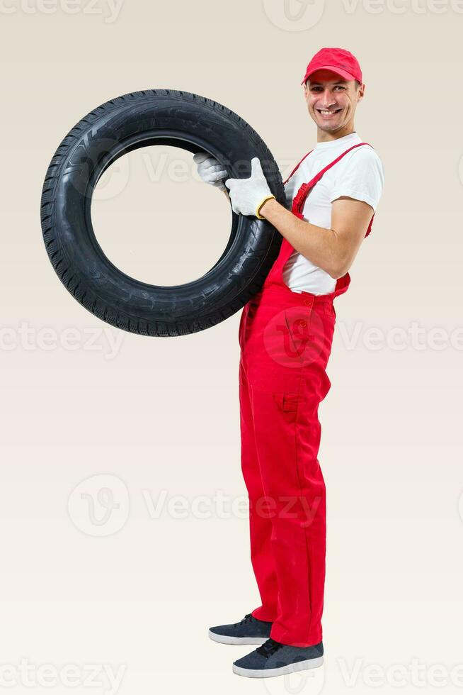 working man in full growth holds a tire on a white background photo