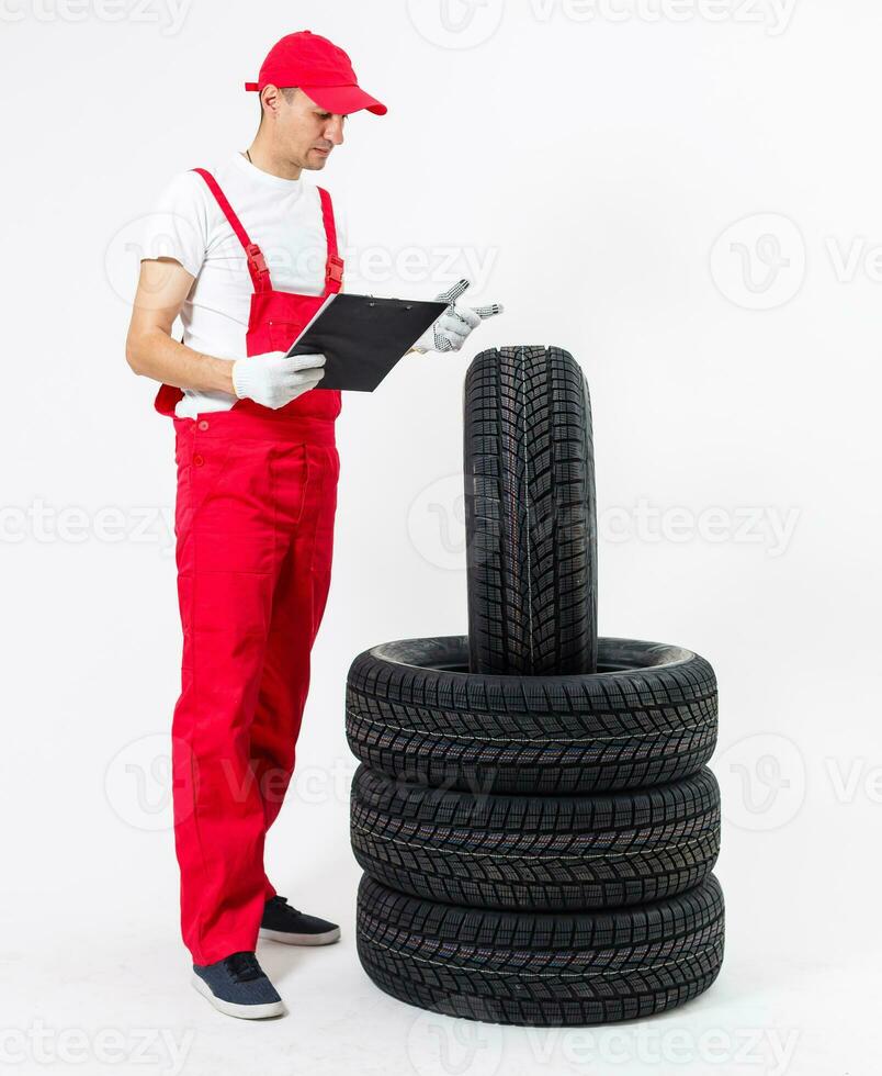 mecánico sosteniendo un neumático en el taller de reparación. sustitución de neumáticos de invierno y verano. foto