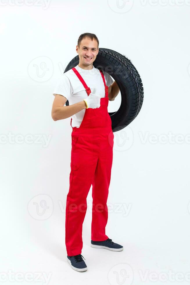 working man in full growth holds a tire on a white background photo