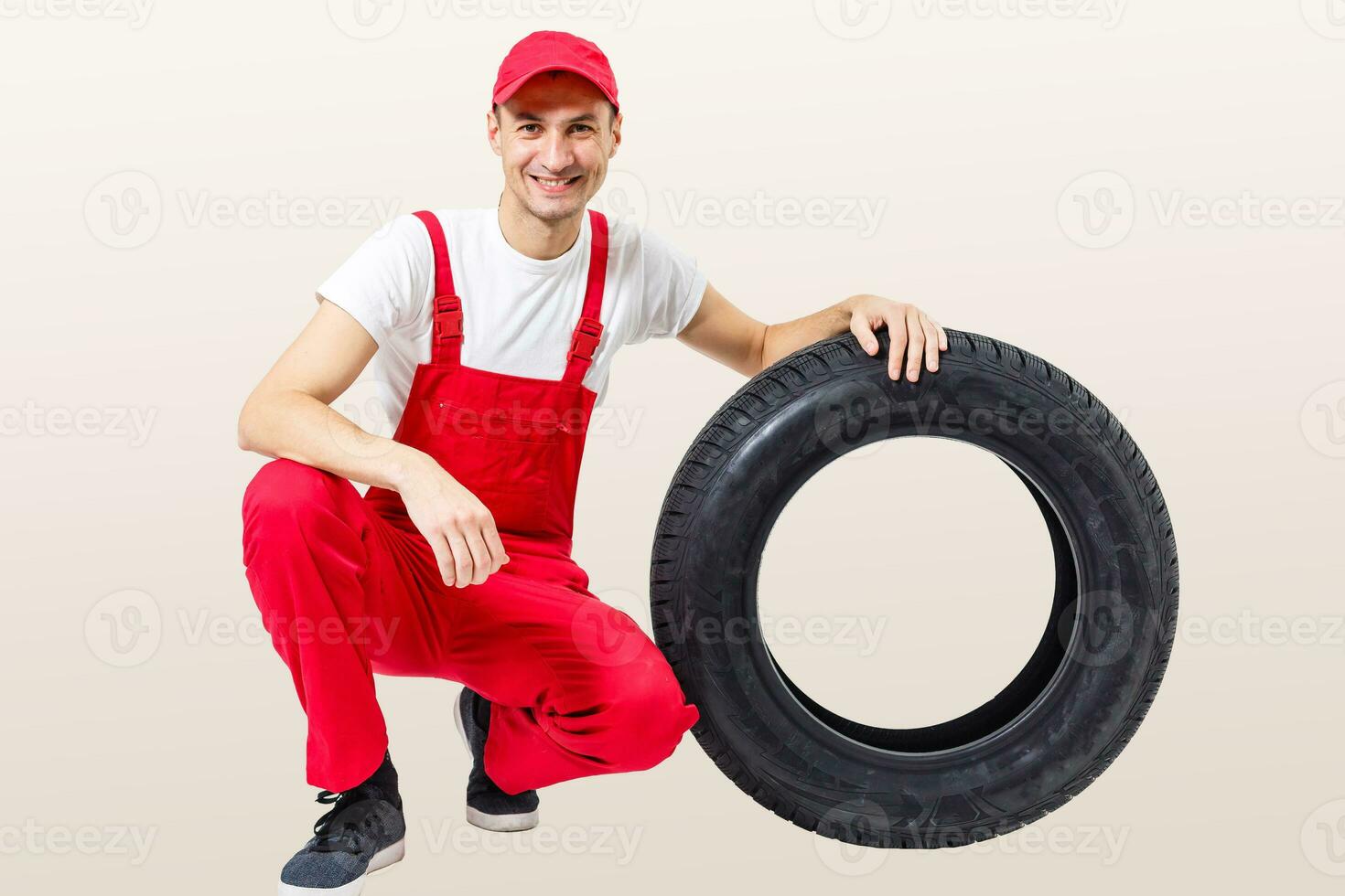 Mechanic carrying a tyre on a white background photo