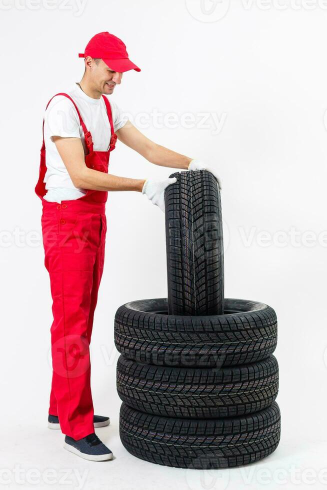 working man in full growth holds a tire on a white background photo