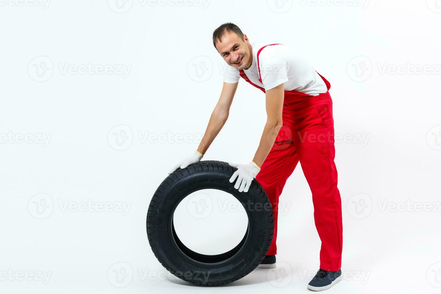 trabajando hombre en lleno crecimiento sostiene un neumático en un blanco antecedentes foto