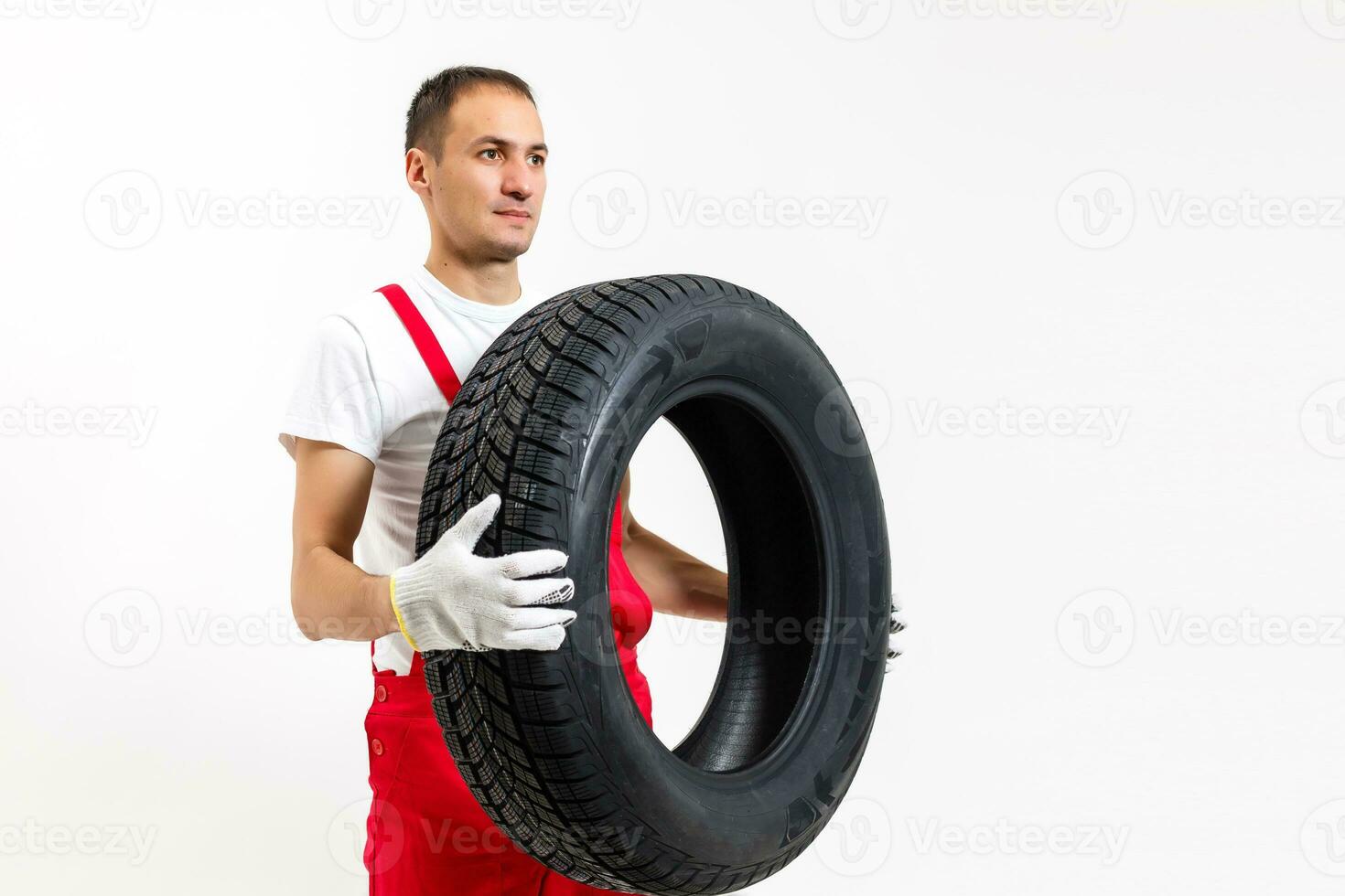 mecánico que lleva un neumático en un blanco antecedentes foto