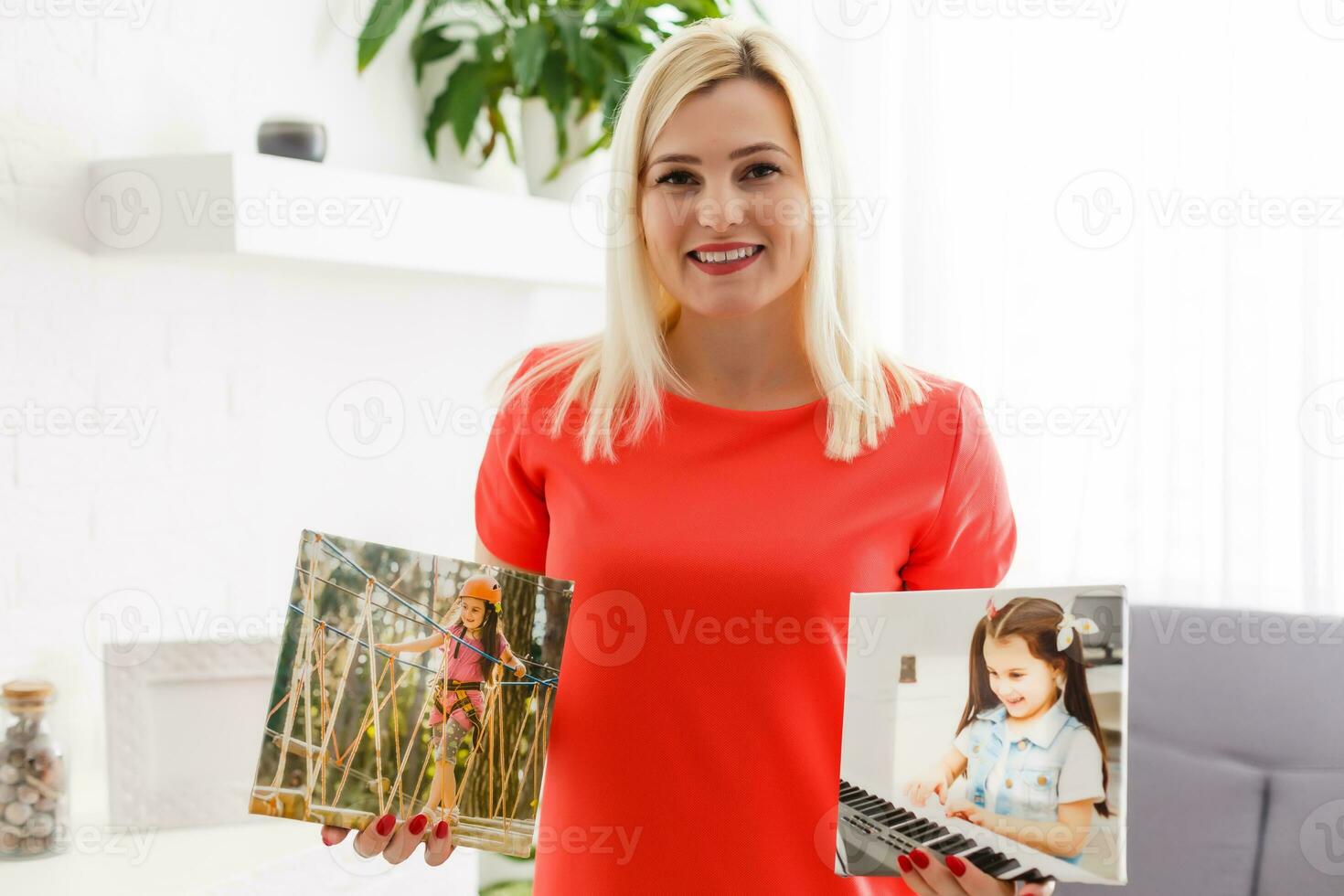 A happy young blonde woman is holding a large wall canvas at home photo