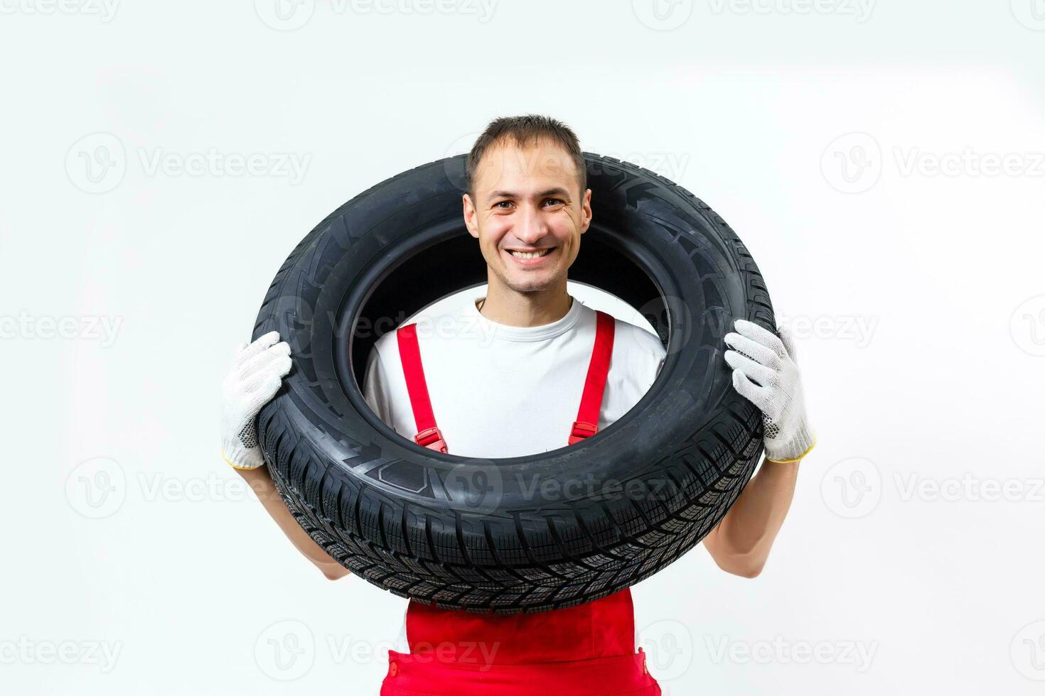 Mechanic carrying a tyre on a white background photo