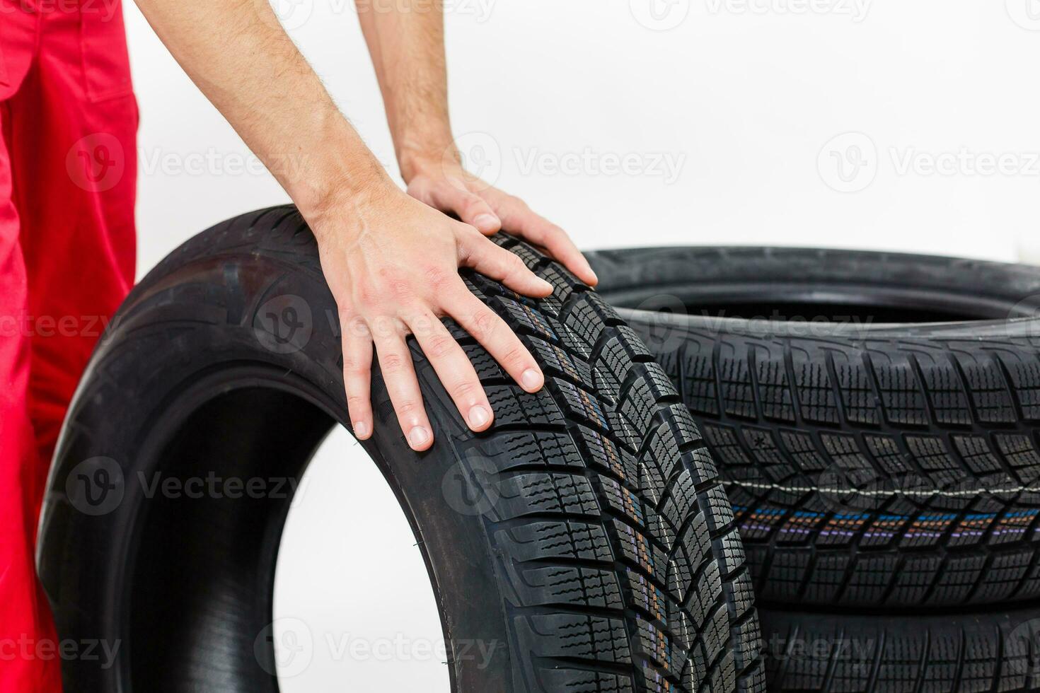 Closeup of mechanic hands pushing a black tire in the workshop. photo