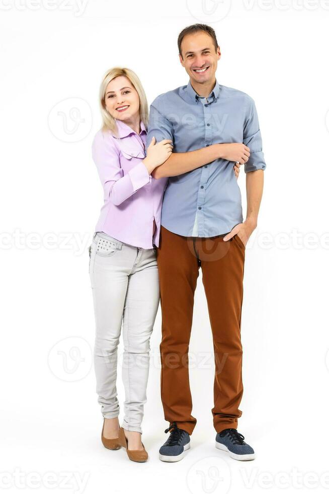 Smiling young couple embracing and standing full length isolated on white background photo