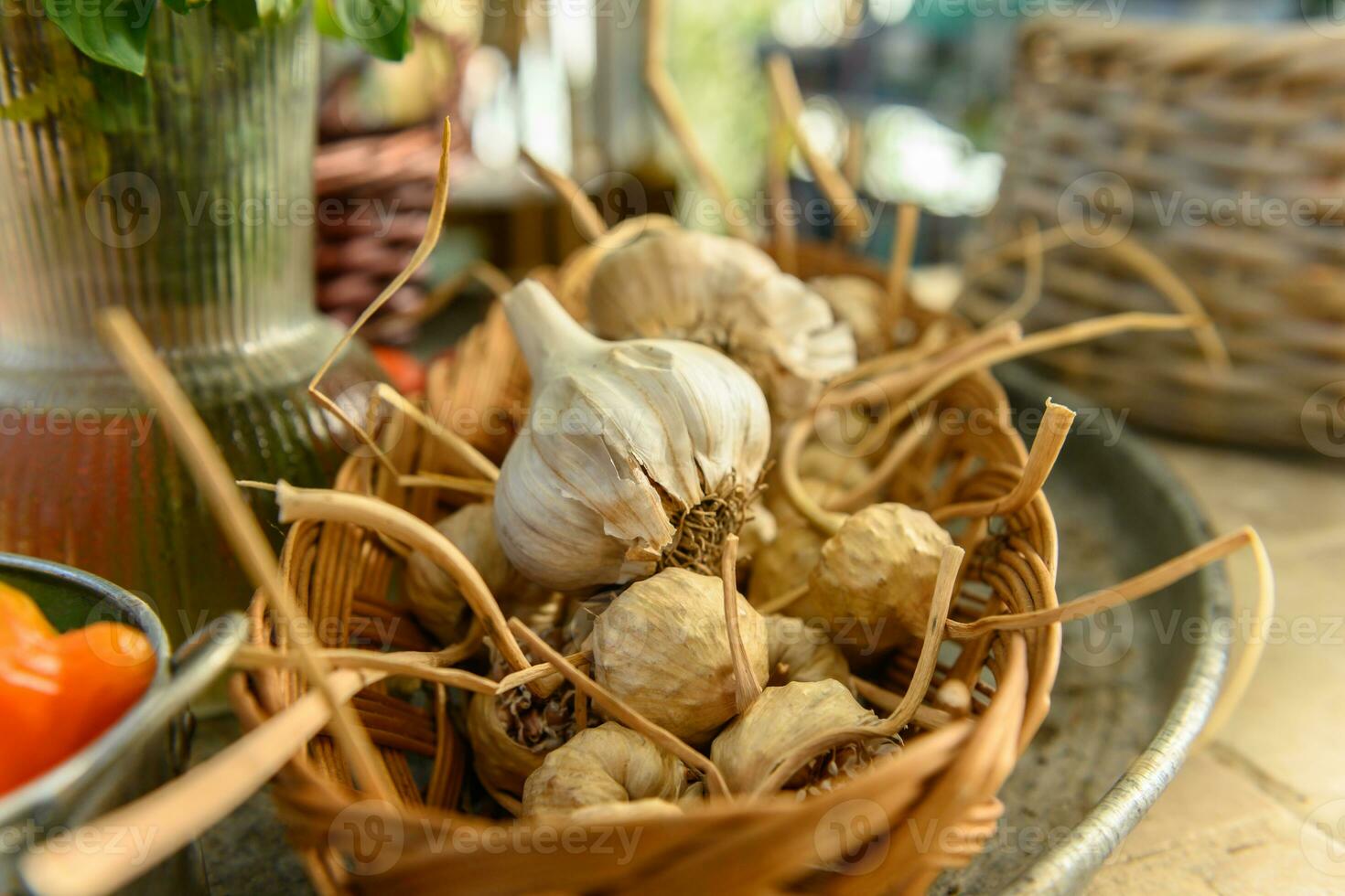 Small wicker basket with garlics on a rustic tray photo