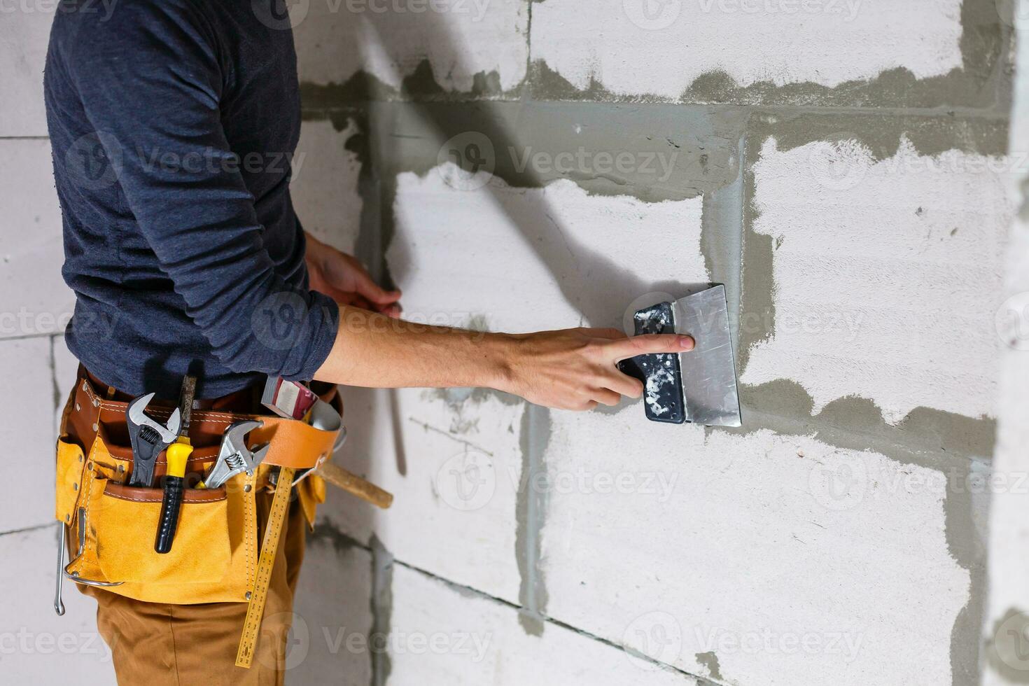 Worker wipes the seams outside the brick house. The builder processes the brickwork. Construction mason worker bricklayer installing red brick with trowel putty knife outdoors. photo