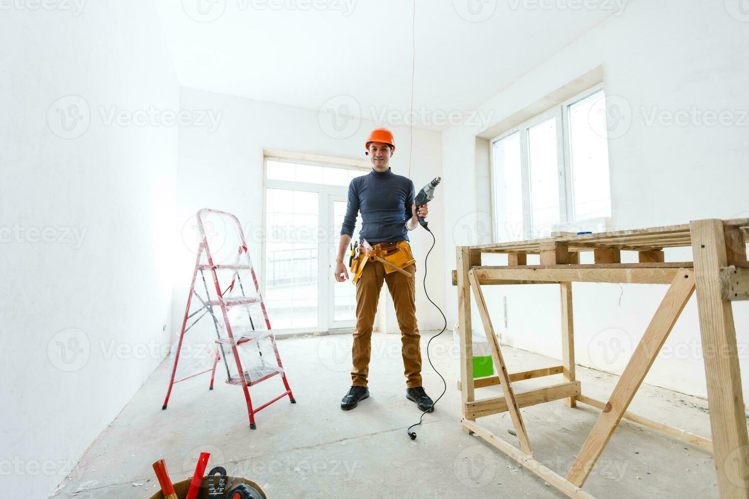 The builder in a protective helmet holds the professional puncher-hammer with a drill of the big diameter photo