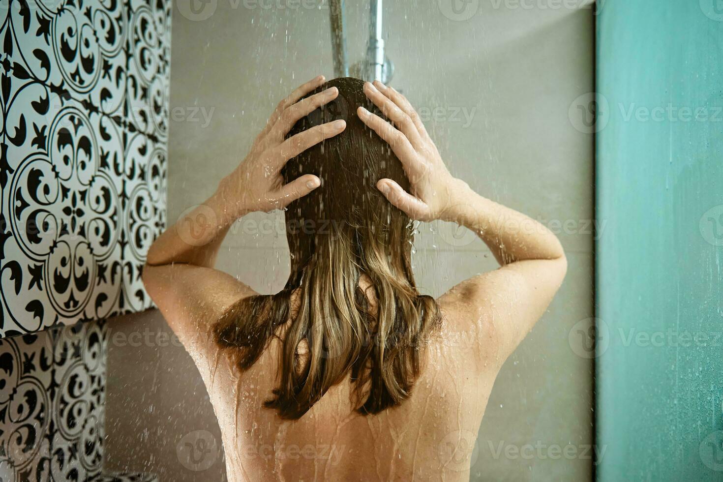 espalda ver de mujer tomando un ducha en baño foto