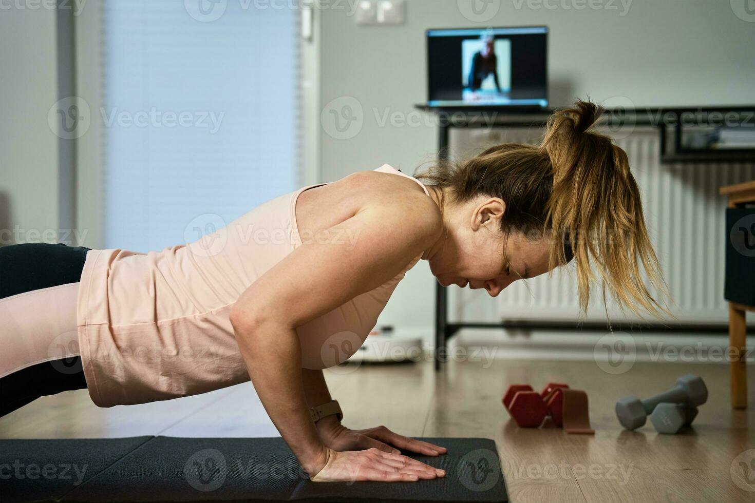 mujer en Deportes ropa lo hace aptitud cardio ejercicios a hogar, utilizando ordenador portátil foto