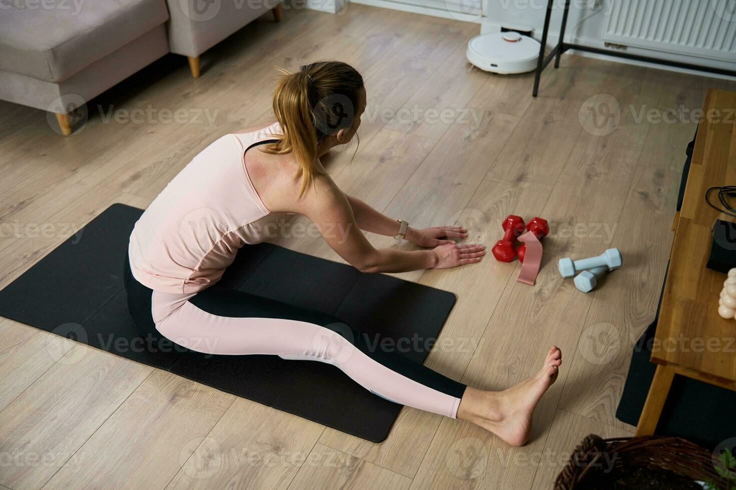 Woman in sports clothes does fitness cardio exercises at home, using laptop photo