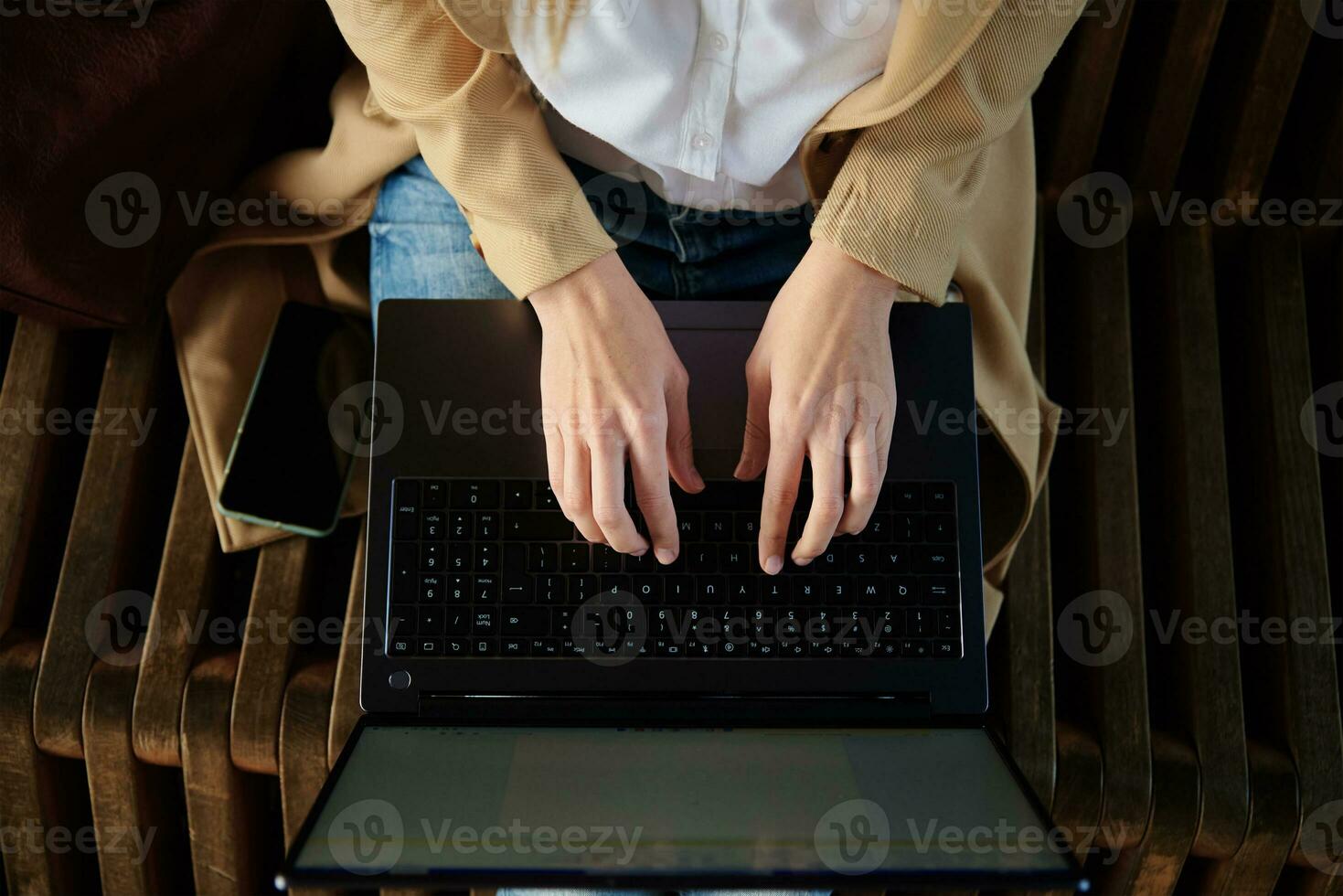 mujer sentado en banco y mecanografía en ordenador portátil teclado foto