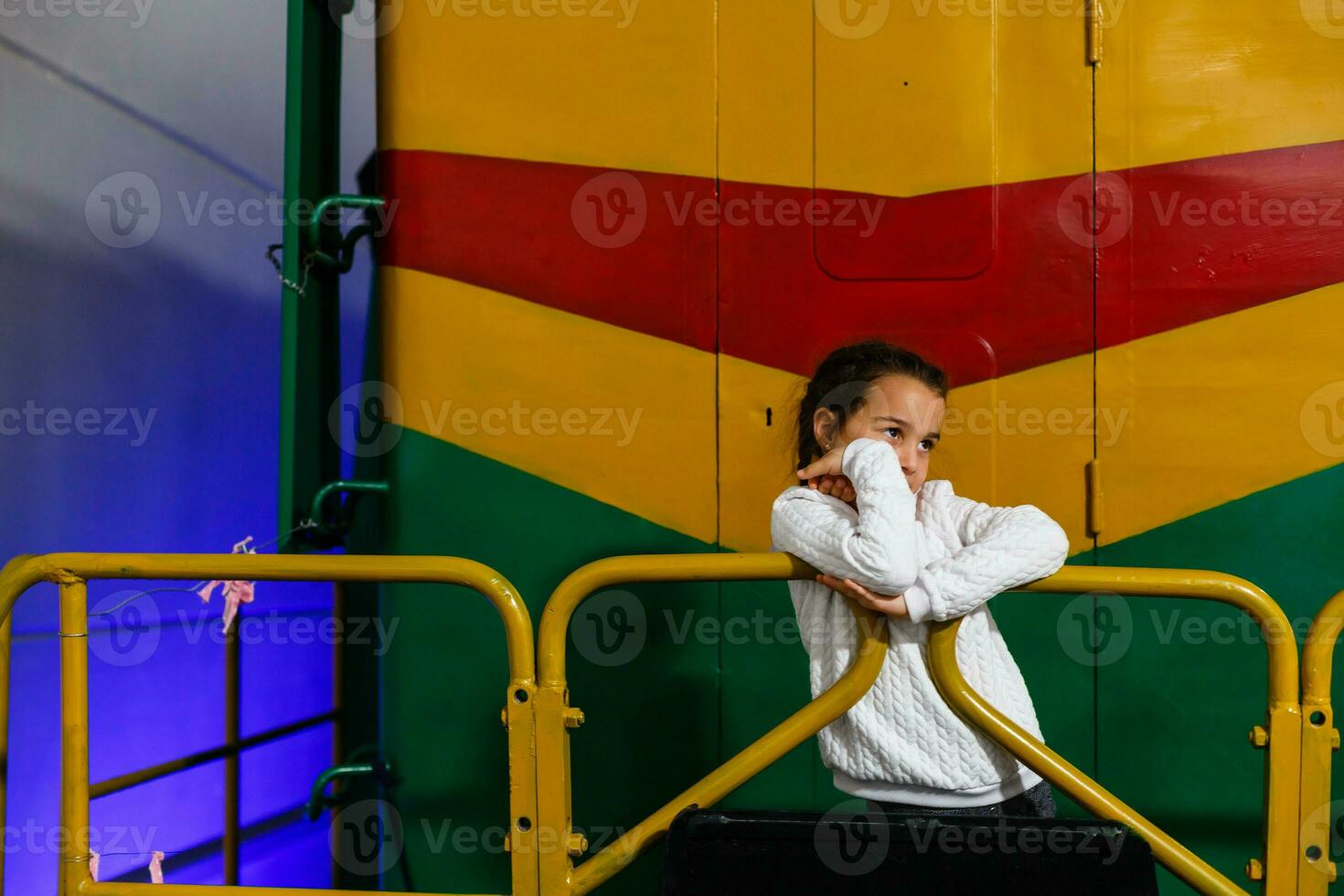 un pequeño niña soportes siguiente a un grande locomotora. foto