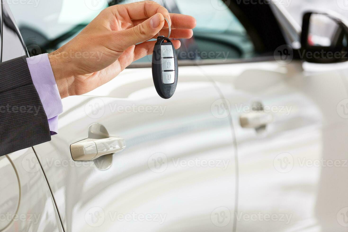 Smiling car salesman handing over your new car keys, dealership and sales concept photo