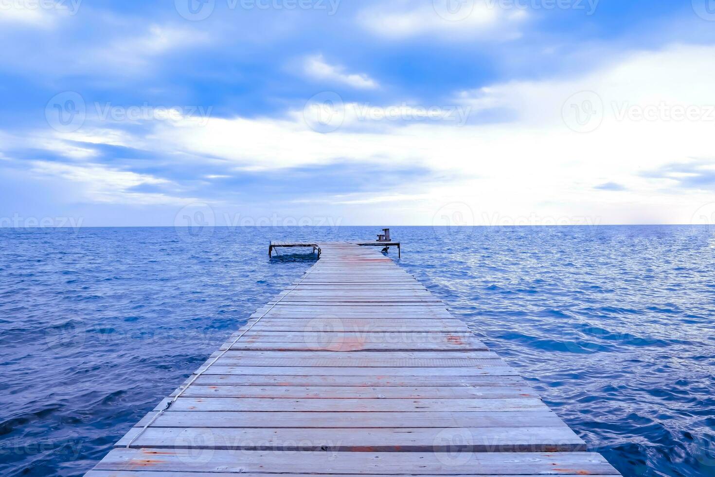 Wooden pier stretches to the sea of against blue sky. photo