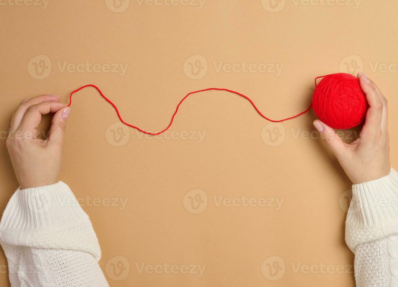 dos hembra manos participación un pelota de rojo de lana hilos para tejido de punto, parte superior ver foto