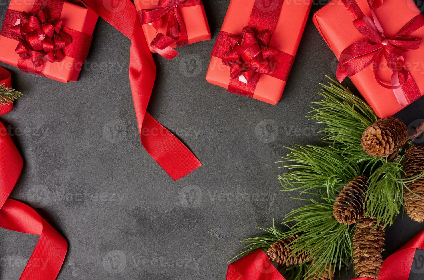 Christmas gifts and fir branch with pine cones on a black background, top view photo