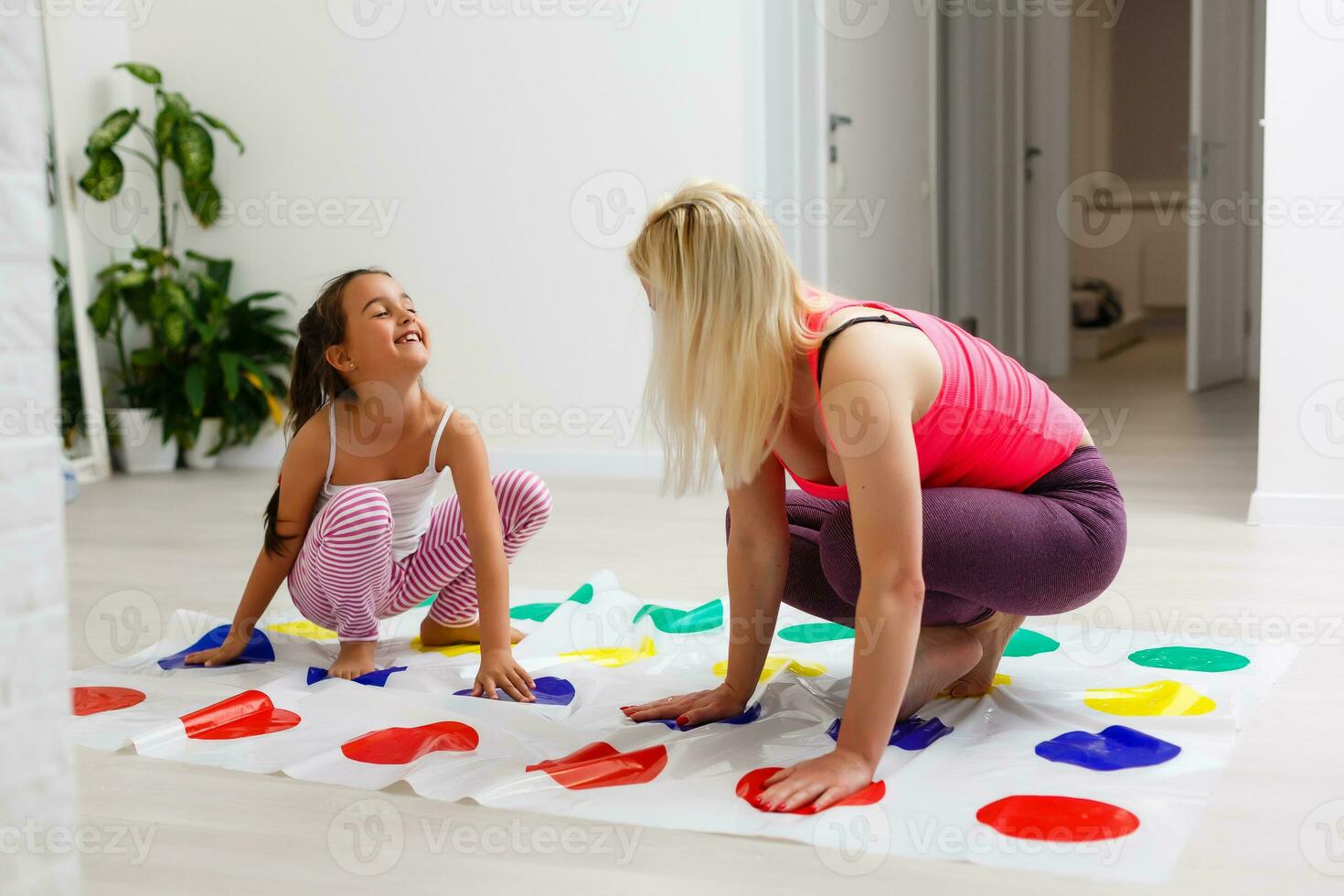 Young mother playing twister with her kids. Cheerful family at home. Happy family having a fun together. photo