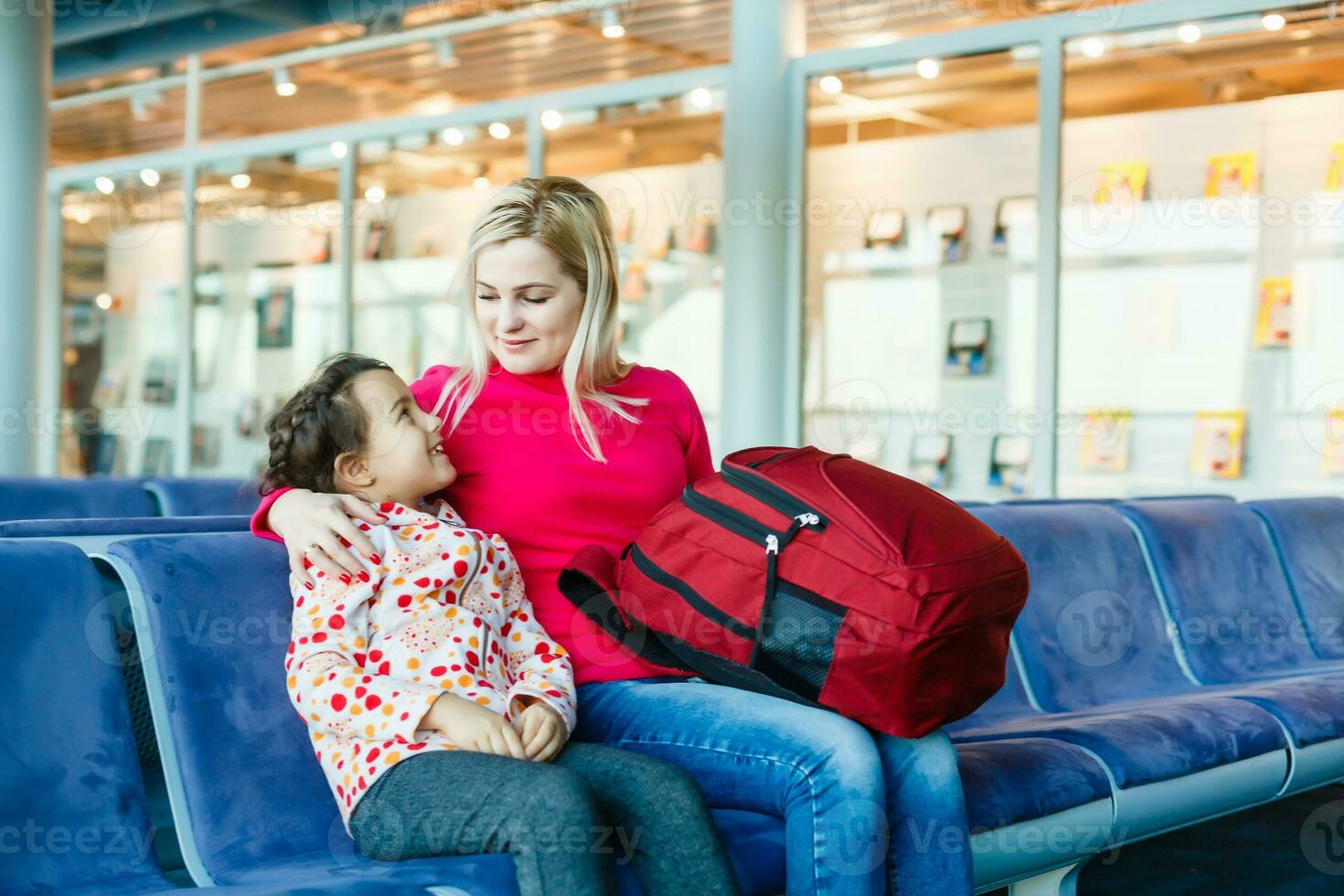 happy young mother with daughter at airport while waiting for their flight photo