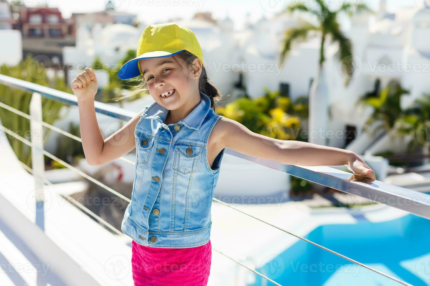 Beautiful little girl spread her arms standing near swimming pool photo