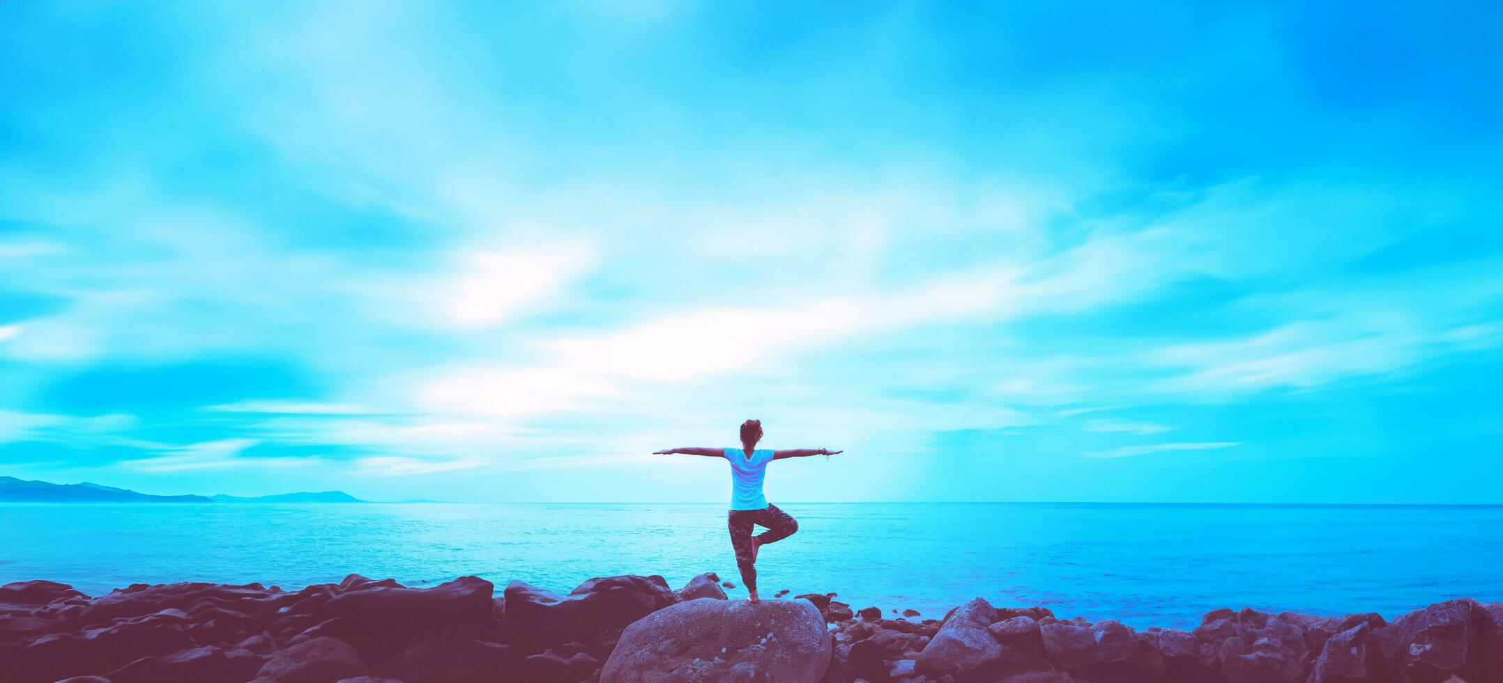 Asian woman travel relax in the holiday. Play if yoga. On the rocks by the sea. photo