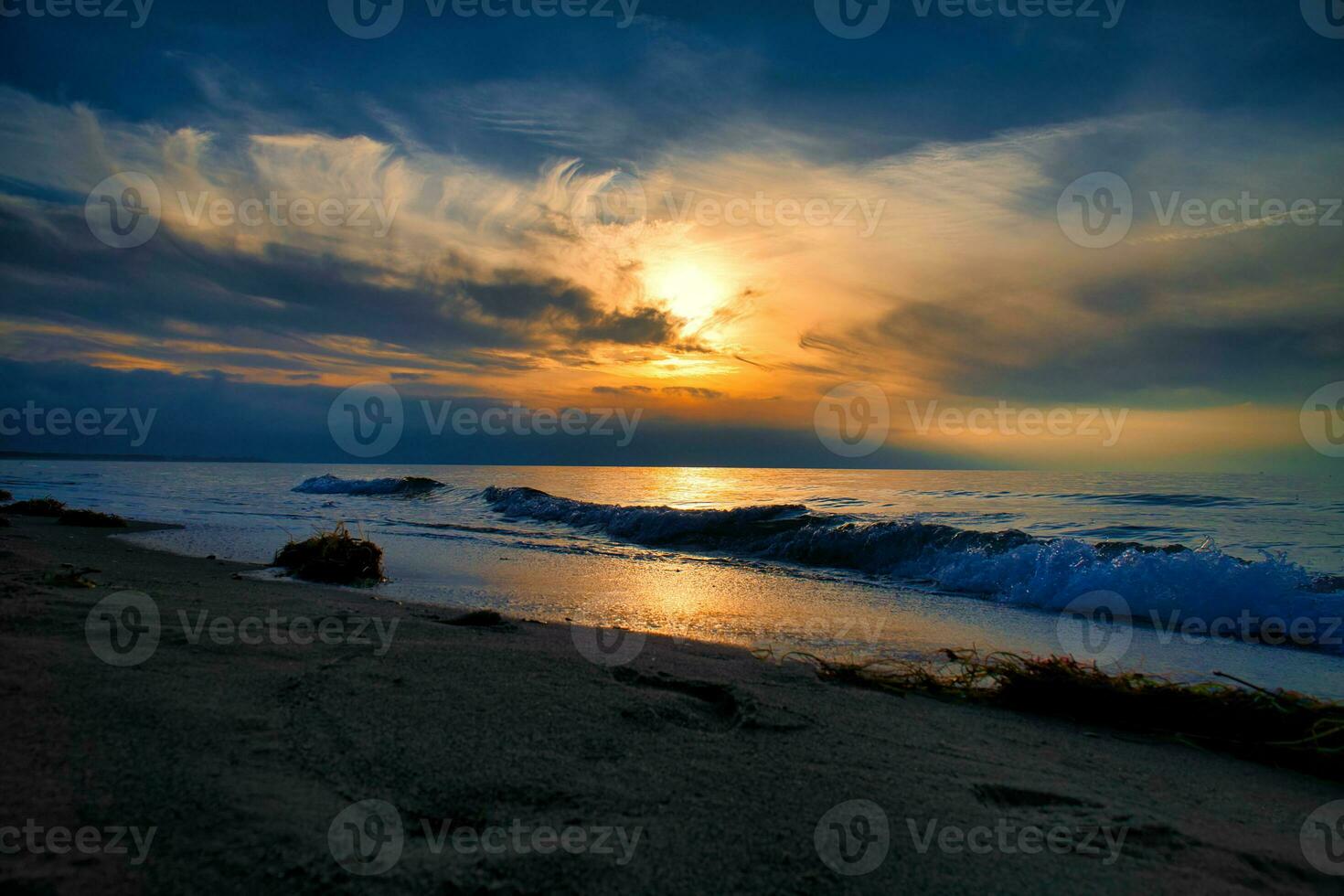 Sunset on the west beach on the Baltic Sea. Waves, beach, cloudy sky and sunshine photo