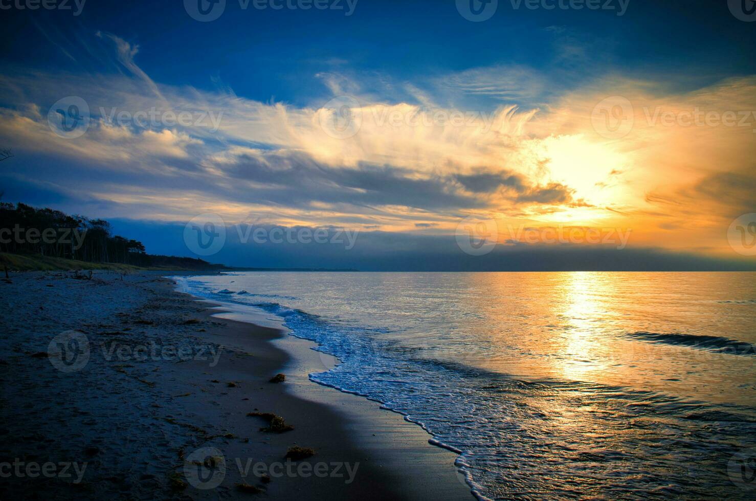 puesta de sol en el Oeste playa en el báltico mar. ondas, playa, nublado cielo y Brillo Solar foto