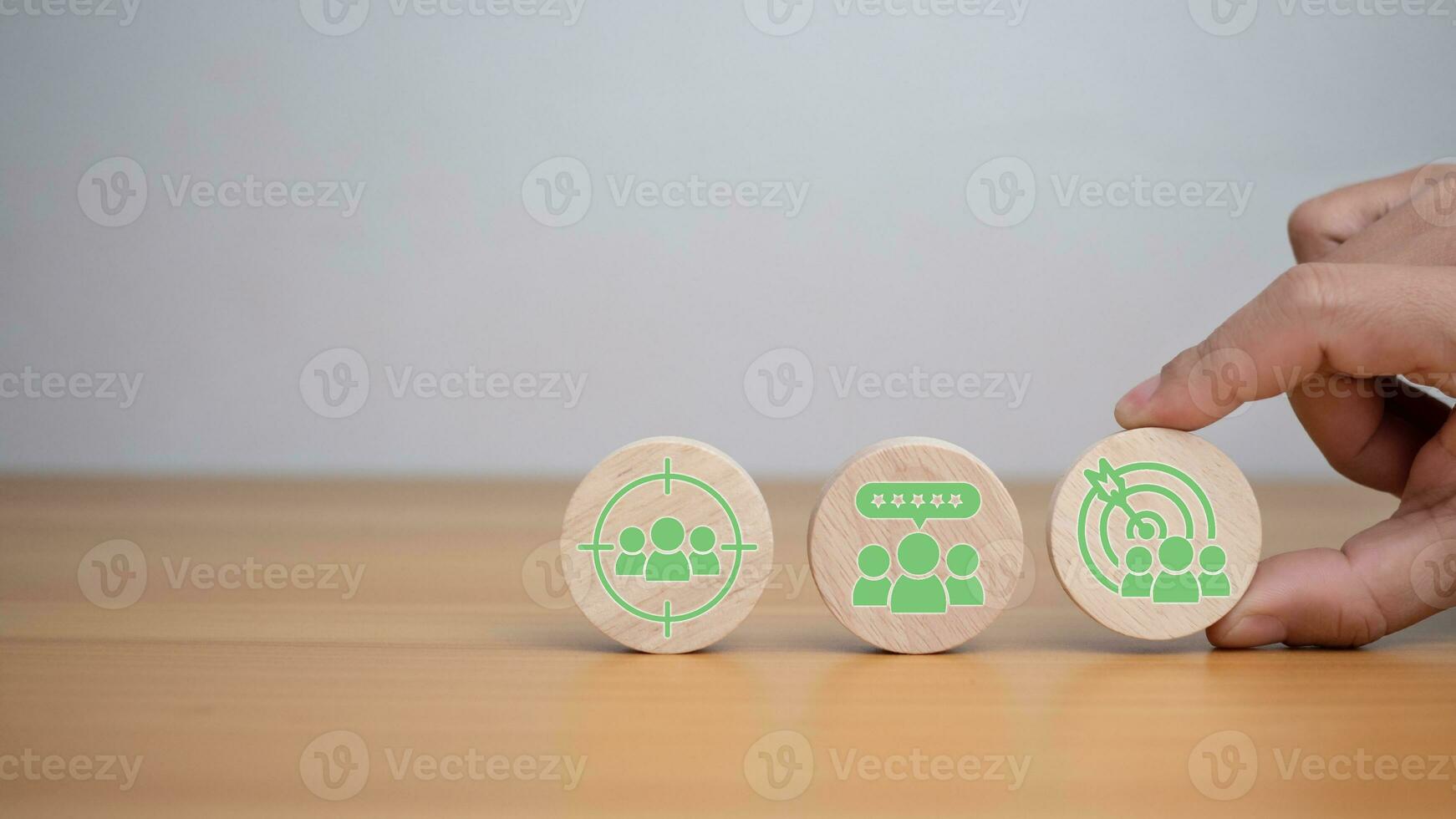 Human hands hold target customer icons on circle wooden planks. Placed on a wooden background, it represents selected business goals, target customers, marketing plans photo