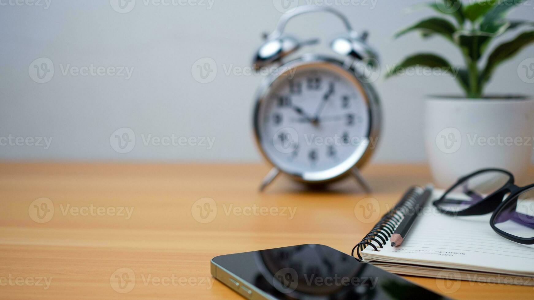 oficina mesa de moderno lugar de trabajo con cuadernos y lápices, teléfono, reloj en de madera mesa. lado ver y Copiar espacio en de madera piso, plano poner, lado ver oficina mesa con lentes. foto