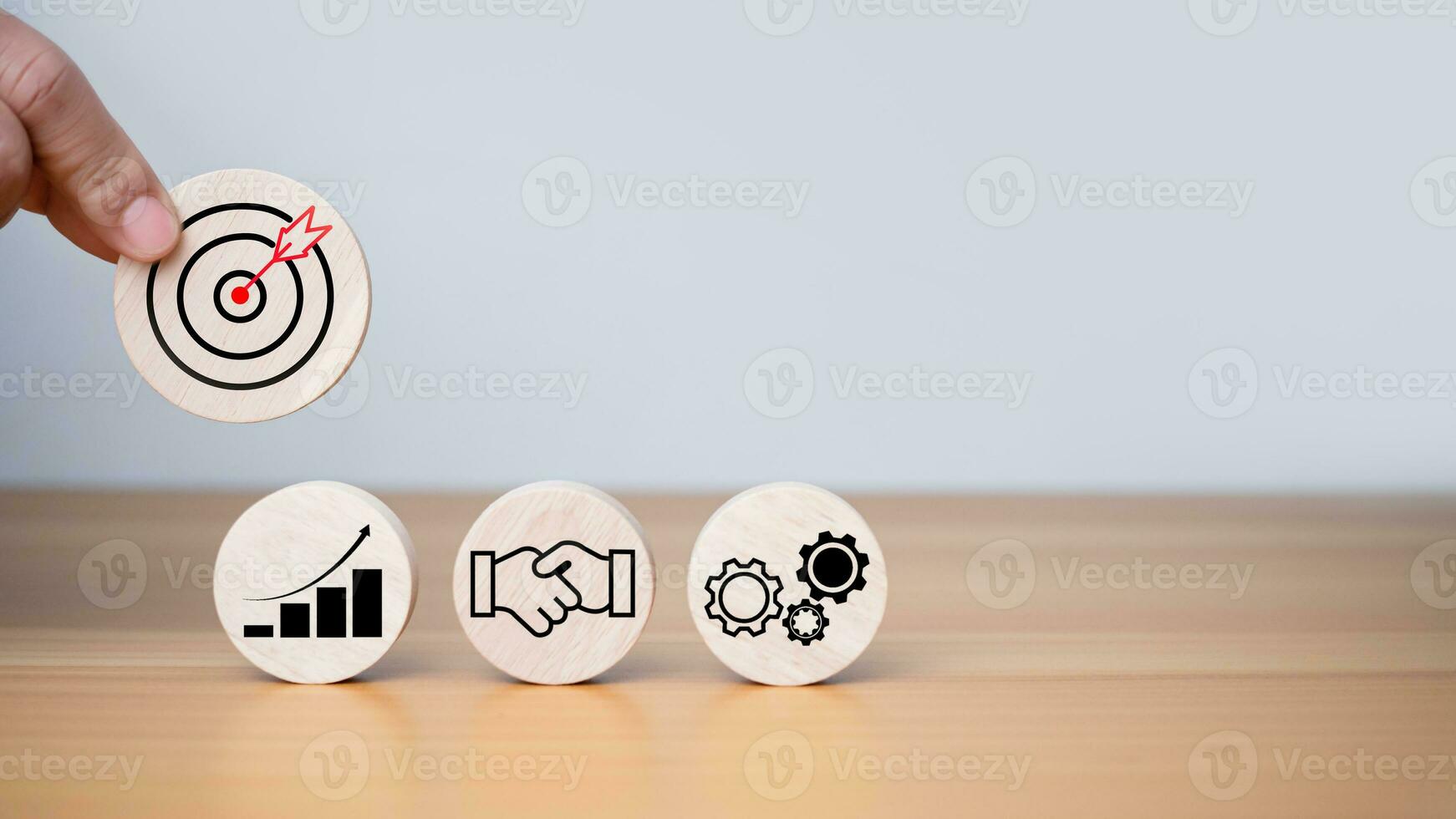Businessman's hands hold a circular wooden board with printed target icons, business goals and objectives concept, business competition. photo