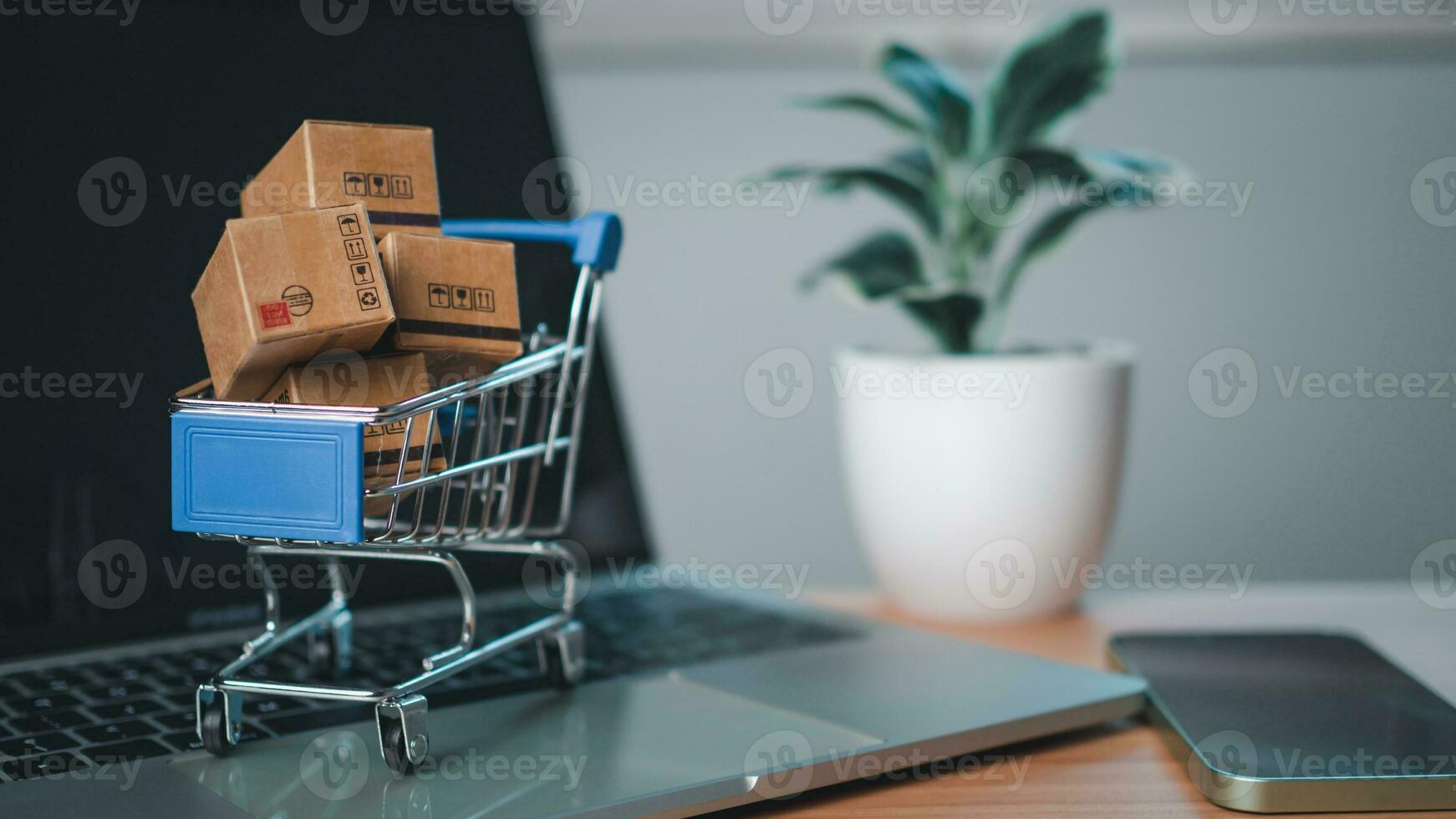 Shopping cart and product boxes placed on laptop computer represent online shopping concept, website, e-commerce, marketplace platform, technology  and online payment concept. photo