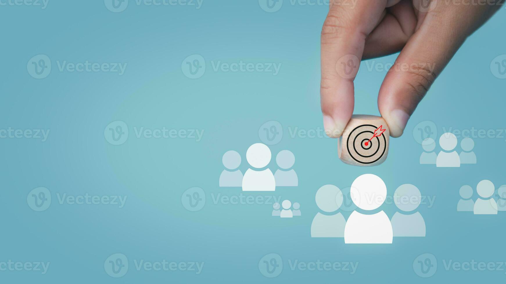 Human hand holds a dart board icon drawn on a wooden block and connects to a target customer on a light blue background It represents the selection of business goals. Marketing plans and strategies. photo