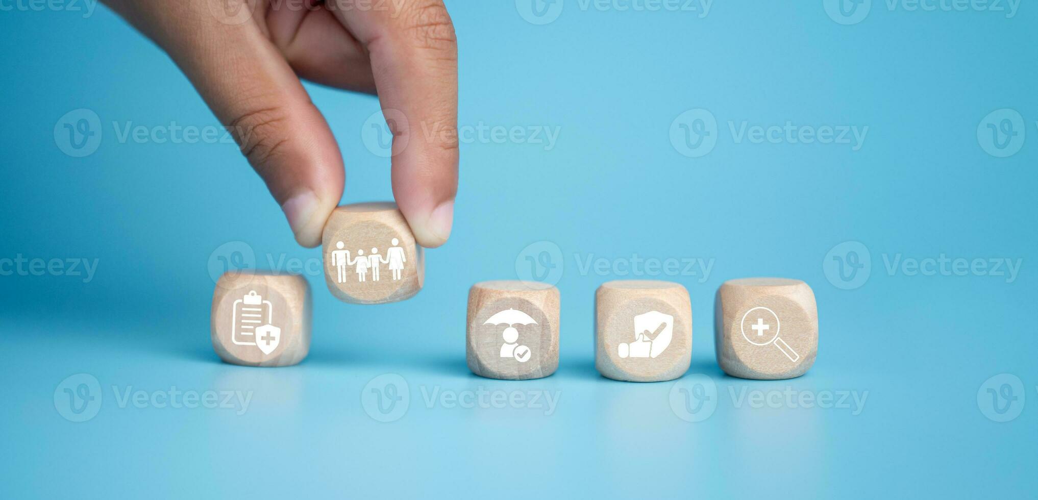 Health insurance and healthcare concept, human hand holds wooden block with icons about health insurance and healthcare access, retirement planning on blue background. photo