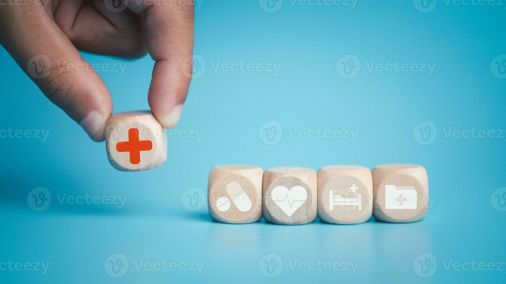 Health and medical concept Human hand holds a wooden block with icons about health and access to treatment and medicine and supplies on a blue background. photo