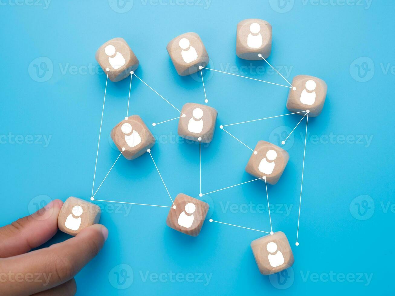 Human hand holding customer icons drawn on wooden blocks and connected together on a light blue background. Represents the selection of business goals, target customers, marketing plans and strategies photo